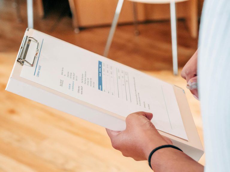 Close-up of hands holding a clipboard with business documents, indicating analysis and planning.